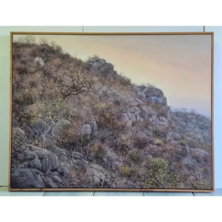 An artwork of the side of a hill with rocks and bushes in a wooden frame.