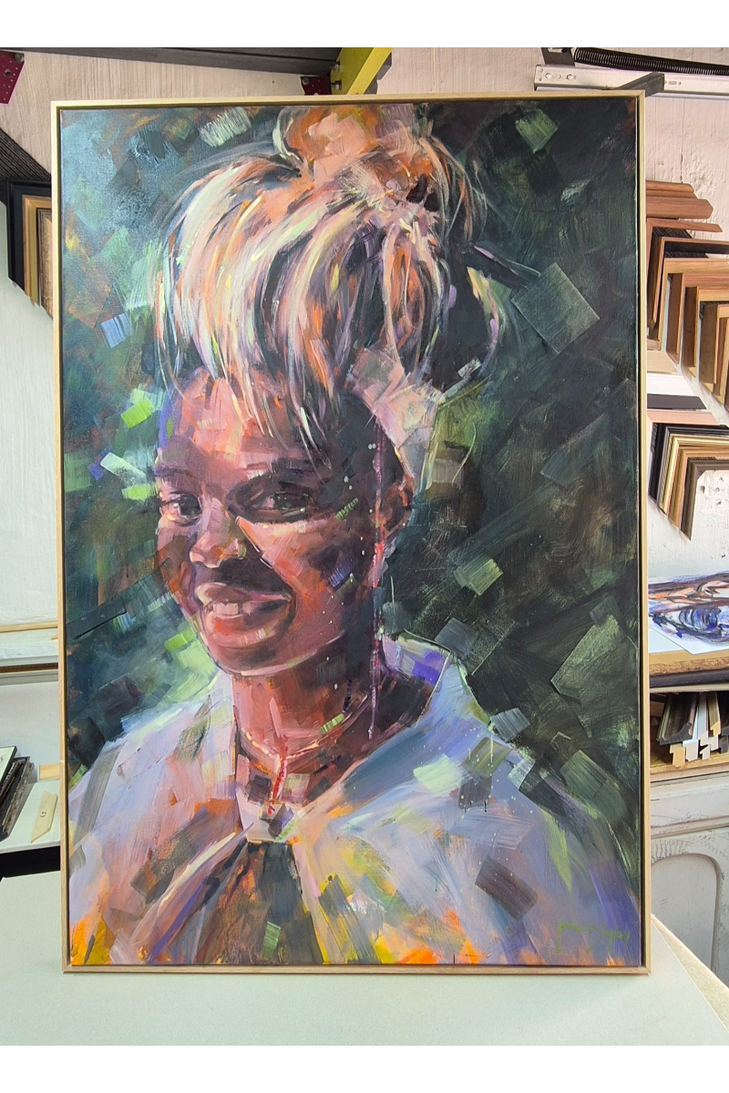 A painting of a girl smiling that is framed with a wooden border.