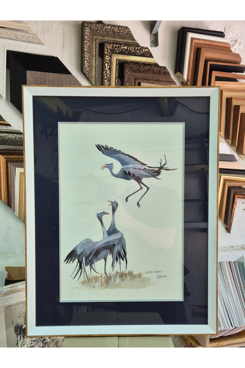 A framed piece of artwork of three herons.